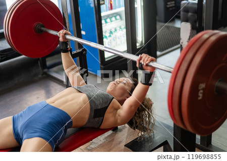 Middle aged woman doing bench press at the gym. Middle aged woman doing bench press at the gym. 119698855