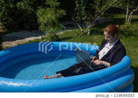 Caucasian business woman working on laptop while sitting in swimming pool. Caucasian business woman working on laptop while sitting in swimming pool. 119698883