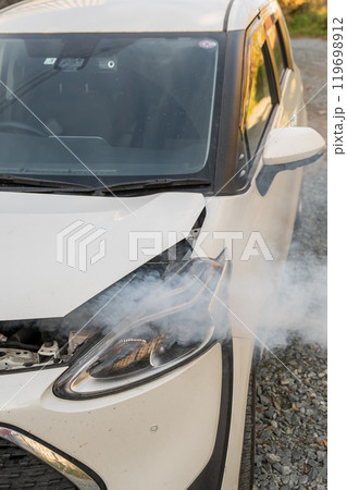 Smoke is coming from under the hood of the car. Smoke is coming from under the hood of the car. 119698912