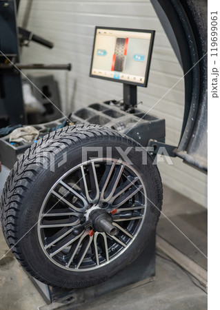 Mechanic balancing a wheel in a workshop. Mechanic balancing a wheel in a workshop. 119699061