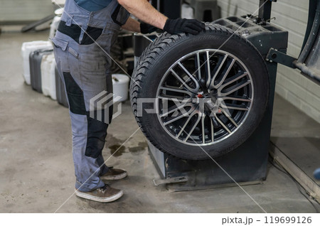 Mechanic balancing a wheel in a workshop. Mechanic balancing a wheel in a workshop. 119699126
