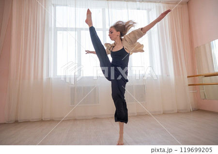 Caucasian woman dances contemporary in ballet class. Dancer in a jump.  119699205