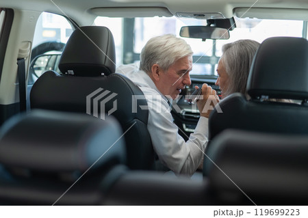 Mature Caucasian couple sitting in a new car and rejoicing at the purchase.  119699223