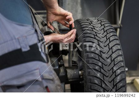 Mechanic removes wheel balance weight from car wheel. Mechanic removes wheel balance weight from car wheel. 119699242