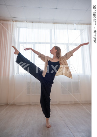 Caucasian woman dances contemporary in ballet class. Dancer in a jump. Vertical photo. Caucasian woman dances contemporary in ballet class. Dancer in a jump. Vertical photo. 119699380