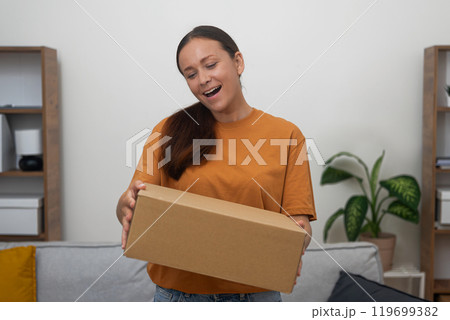 Excitement radiates from lady as she receives her desired package, a testament to the joy of internet shopping Excitement radiates from lady as she receives her desired package, a testament to the joy of internet shopping 119699382