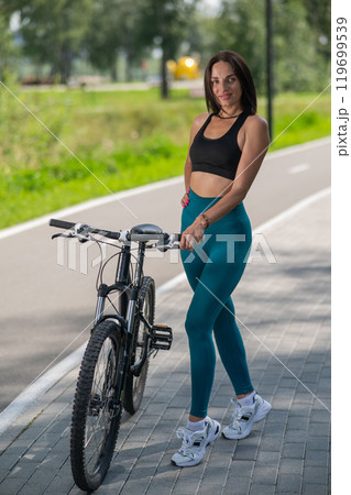 Caucasian woman riding a bike in a park. Vertical photo.  119699539