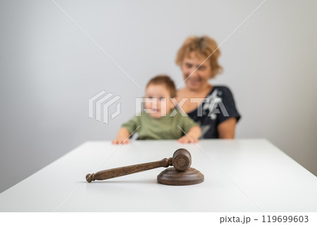 An elderly woman holds a child behind a judge's gavel. An elderly woman holds a child behind a judge's gavel. 119699603