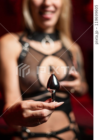 Woman holding steel anal plug against chest. Woman holding steel anal plug against chest. 119699605