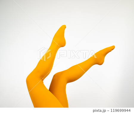 Female legs in ocher tights on a white background.  119699944