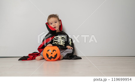 Little Caucasian boy in Dracula costume holding basket for sweets on white background. Trick or treat.  119699954