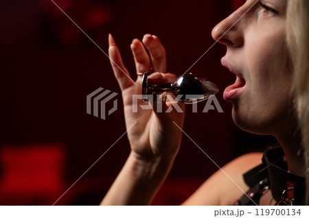Caucasian woman holds steel anal plug in mouth. Caucasian woman holds steel anal plug in mouth. 119700134