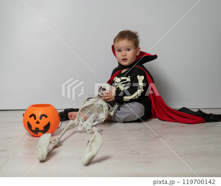 Little Caucasian boy in Dracula costume holding skull on white background. Little Caucasian boy in Dracula costume holding skull on white background. 119700142