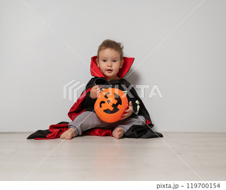 Little Caucasian boy in Dracula costume holding basket for sweets on white background. Trick or treat. Little Caucasian boy in Dracula costume holding basket for sweets on white background. Trick or treat. 119700154