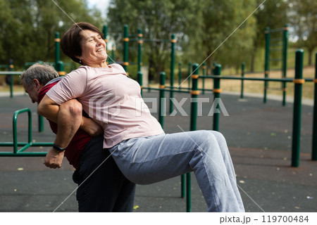 Concept of healthy lifestyle for elderly. Married couple raise each other and stretch each other hands 119700484