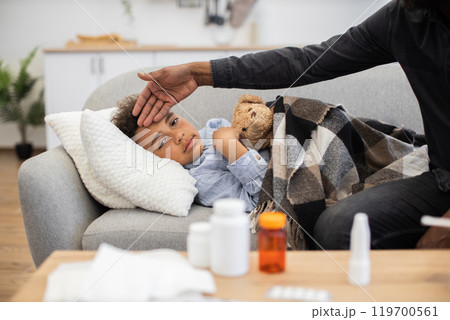 Father checking temperature of sick child on couch 119700561