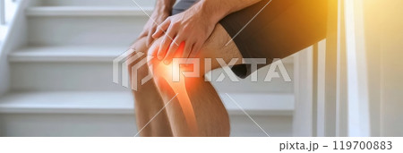 Man holding knee in pain, possibly due to injury or medical condition. Image shows discomfort and suffering, indicating need for medical attention Man holding knee in pain, possibly due to injury or medical condition. Image shows discomfort and suffering, indicating need for medical attention 119700883