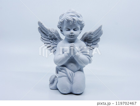A white angel statue kneels and prays with eyes closed A white angel statue kneels and prays with eyes closed 119702467