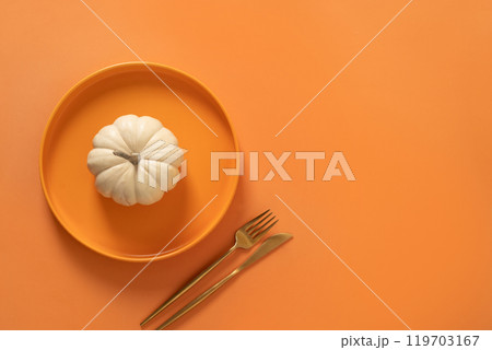 Autumn and Thanksgiving Day table setting with white small pumpkin, orange empty plate with golden cutlery on orange background. Concept catering. Top view. Copy space. 119703167