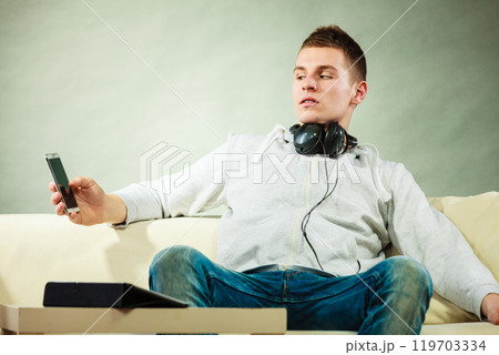 man on couch with headphones smartphone and tablet man on couch with headphones smartphone and tablet 119703334