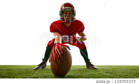 Focused man, American football player in helmet and re uniform standing on field with ball, showing determination to win 119703373
