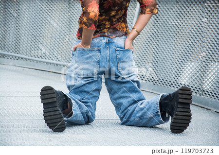 closeup of young woman wearing a large blue jeans trousers in the street closeup of young woman wearing a large blue jeans trousers in the street 119703723
