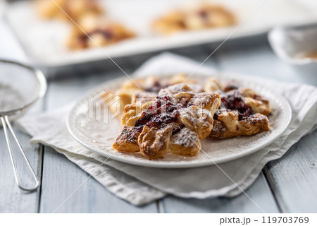 Sweet dessert pastries made of puff pastry with strawberry jam filled with caramelized apple sprinkled with powdered sugar 119703769