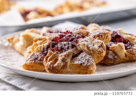 Sweet dessert pastries made of puff pastry with strawberry jam filled with caramelized apple sprinkled with powdered sugar Sweet dessert pastries made of puff pastry with strawberry jam filled with caramelized apple sprinkled with powdered sugar 119703772
