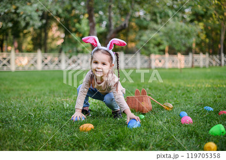 Smiling Little Girl with Bunny Ears and Easter Basket Outdoors Smiling Little Girl with Bunny Ears and Easter Basket Outdoors 119705358