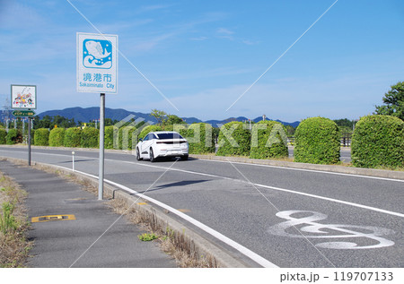 白色の高級乗用車が鳥取県境港市の米子鬼太郎空港沿いのメロディー道路を走る光景 白色の高級乗用車が鳥取県境港市の米子鬼太郎空港沿いのメロディー道路を走る光景 119707133