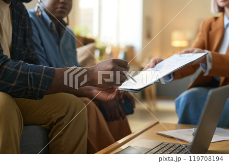 Side view close up of unrecognizable African American man signing contract or invoice form on clipboard during at home consultation with financial expert copy space 119708194