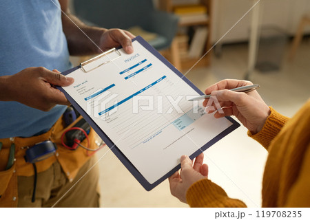 Close up of unrecognizable female client signing contract or invoice form for home repair services on clipboard copy space 119708235