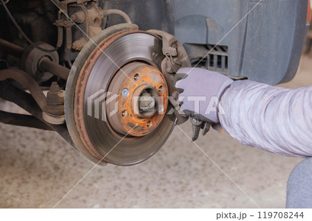 Mechanic performs repair work. Wheel balancing or repair and change auto tire. Technicians are fixing car wheel in garage.  119708244