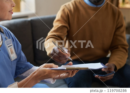Close up of unrecognizable African American man signing contract on clipboard for at home medical services copy space Close up of unrecognizable African American man signing contract on clipboard for at home medical services copy space 119708286