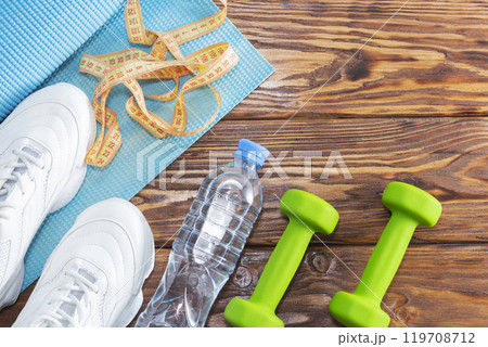 Shoes, water bottle, measuring tape, and dumbbells on a table Shoes, water bottle, measuring tape, and dumbbells on a table 119708712