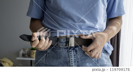 Hands unbuttoning leather belt on jeans Hands unbuttoning leather belt on jeans 119709178