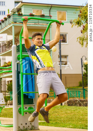 Man doing pull ups in outdoor gym 119710334