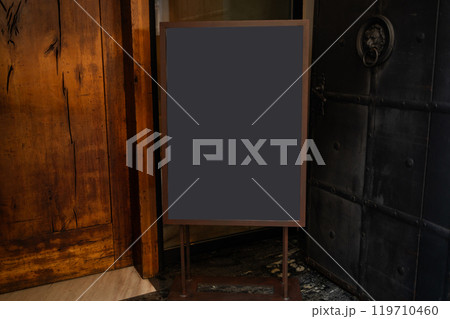 Black blank sheet is placed on located in front of a coffee shop. Blank wood sandwich board standing outdoor cafe, mockup menu advertising design. 119710460