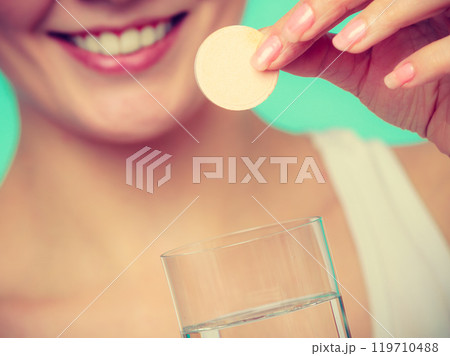 Woman holding glass with water and effervescent tablet 119710488