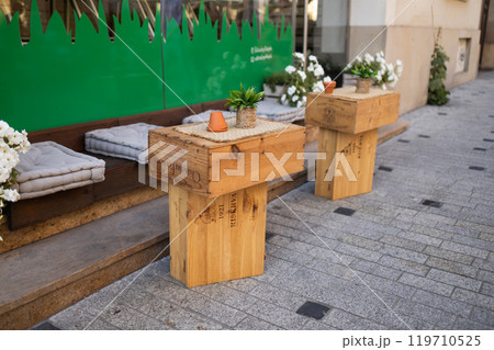 Wooden set of outdoor furniture for a picnic in the autumn garden or cafe. Cozy courtyard with table and chair in village 119710525