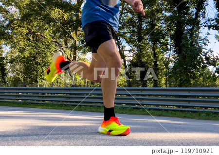 close up legs male runner in bright running shoes run in road 119710921