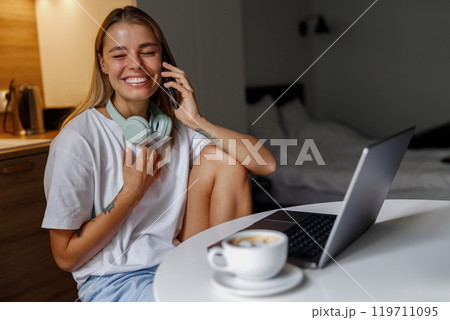 A Young Woman Happily Enjoying Her Coffee While Working from the Comfort of Home 119711095