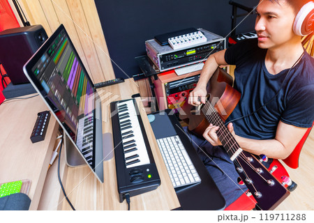 asian male musician, producer playing acoustic guitar for recording in home studio asian male musician, producer playing acoustic guitar for recording in home studio 119711288