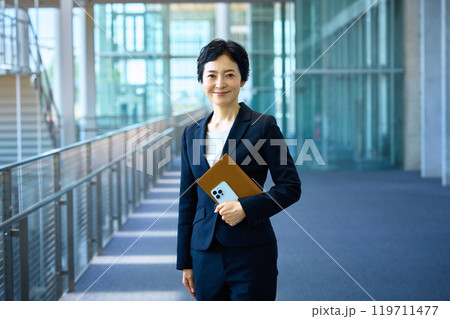 廊下に立つスーツを着たミドルビジネスウーマン 廊下に立つスーツを着たミドルビジネスウーマン 119711477