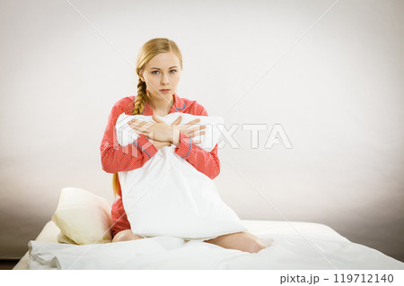 Sad depressed girl in bed gripping pillow Sad depressed girl in bed gripping pillow 119712140