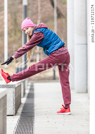 Sporty girl stretching outdoor on city street. 119712174