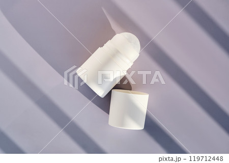 Roll-on deodorant on a purple background with shadow stripes. Roll-on deodorant on a purple background with shadow stripes. 119712448