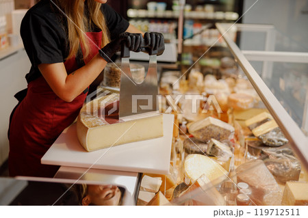 Cheese seller skillfully preparing a variety of delicious cheese in a specialty store 119712511