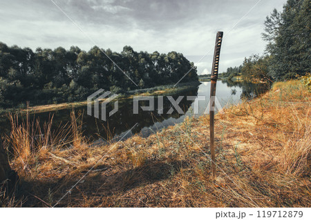 A katana planted in the ground by a river on a cloudy day creates a peaceful and powerful scene. The katana evokes the calm and spirit of a samurai warrior, blending tradition with modern aesthetics. 119712879