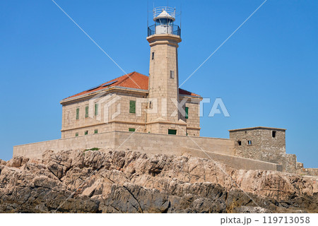 Seaside Lighthouse on Rocky Coast Under Clear Blue Sky Seaside Lighthouse on Rocky Coast Under Clear Blue Sky 119713058